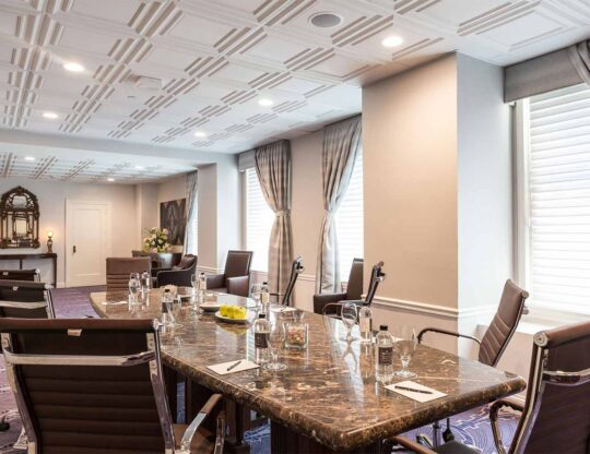 boardroom with a long marble table and brown swivel chairs