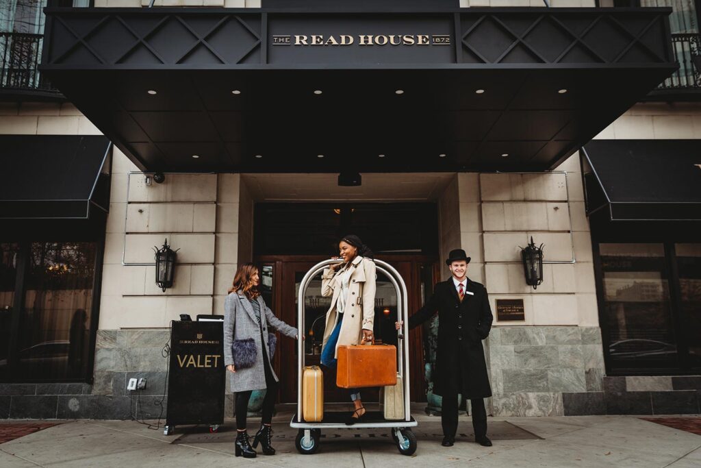 three people standing at the front doors of the read house hotel with a luggage caddy