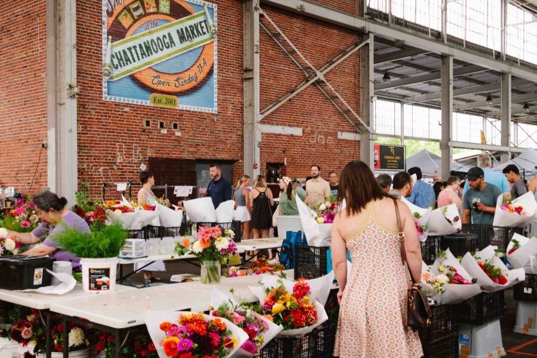 people looking at flowers for sale at a market